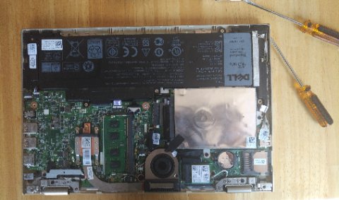 Dell Inspiron laptop bottom panel removed showing internal components and wireless card slot Dell Inspiron laptop bottom panel removed showing internal components and wireless card slot