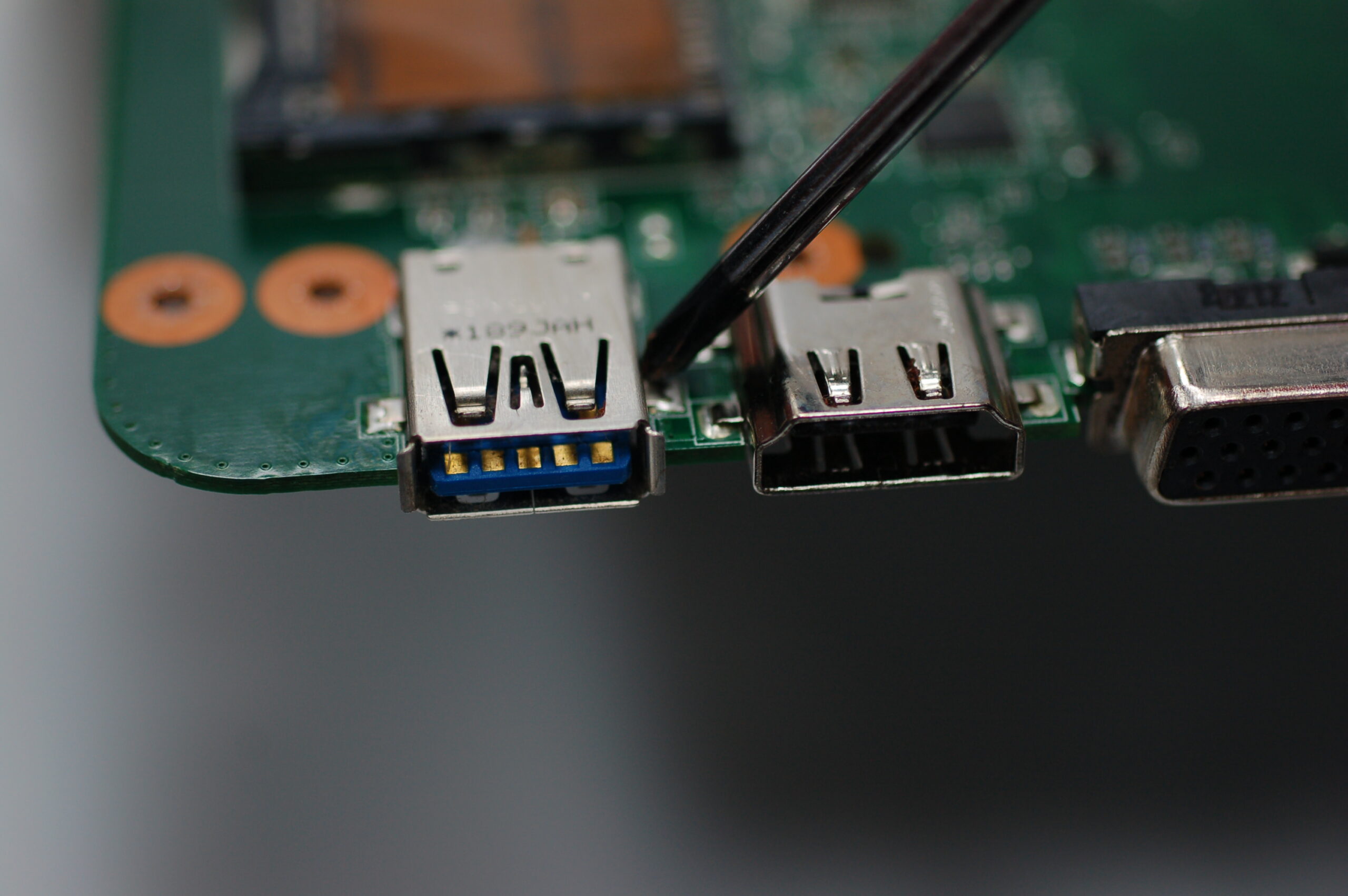 USB-C port solder points on ThinkPad laptop motherboard showing physical damage inspection