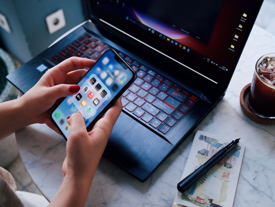 Hands holding a smartphone next to a laptop for Imou Life on PC Hands holding a smartphone next to a laptop for Imou Life on PC